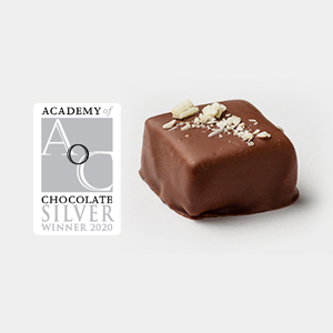 A square chocolate piece with white sprinkles made from single-origin Caribbean cocoa sits next to an Academy of Chocolate Silver Winner 2020 award logo. | Trinitario