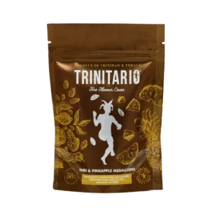 A brown pouch labelled “Trinitario Fine Flavour Cocoa” featuring gold illustrations of cocoa and pineapples, contains handcrafted chocolate nibs and pineapple medallions. | Trinitario