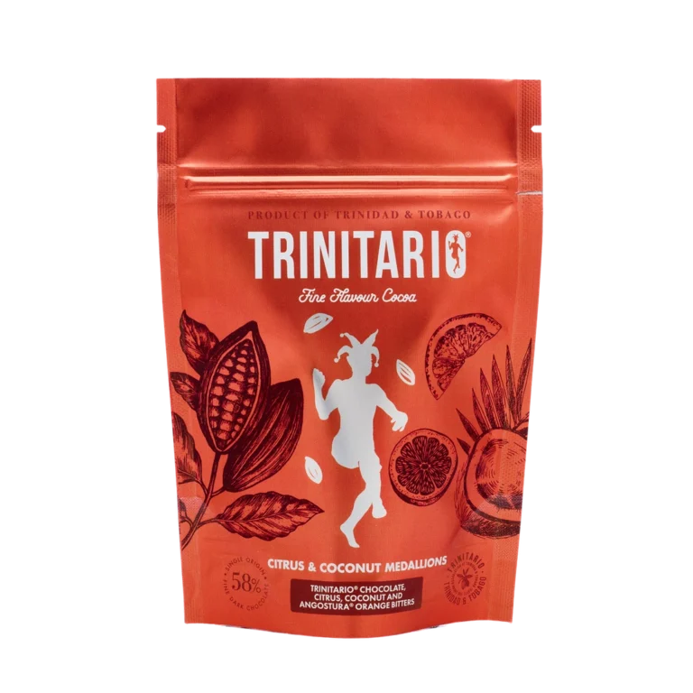 A red resealable pouch labelled "Trinitario Fine Flavour Cocoa" features cocoa pods, citrus fruits, and a dancing goat. The text highlights "Citrus & Coconut Medallions," handcrafted chocolate made with fine flavour cocoa. | Trinitario