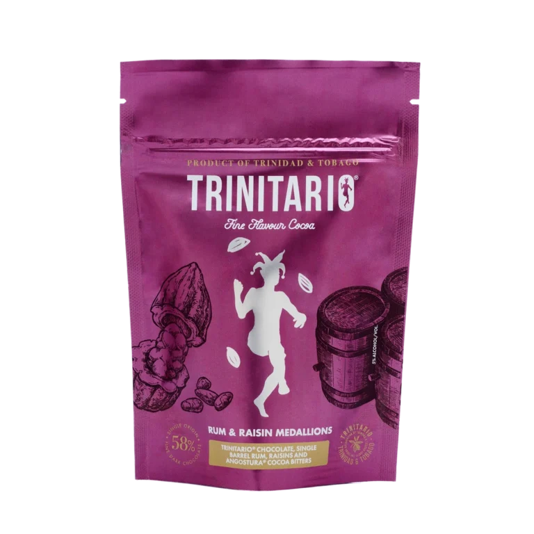 A purple pouch labelled "TRINITARIO Fine Flavour Cocoa," featuring cocoa pods, barrels, and a dancing figure. These Rum & Raisin Medallions are crafted with Caribbean cocoa for a truly fine flavour experience. | Trinitario
