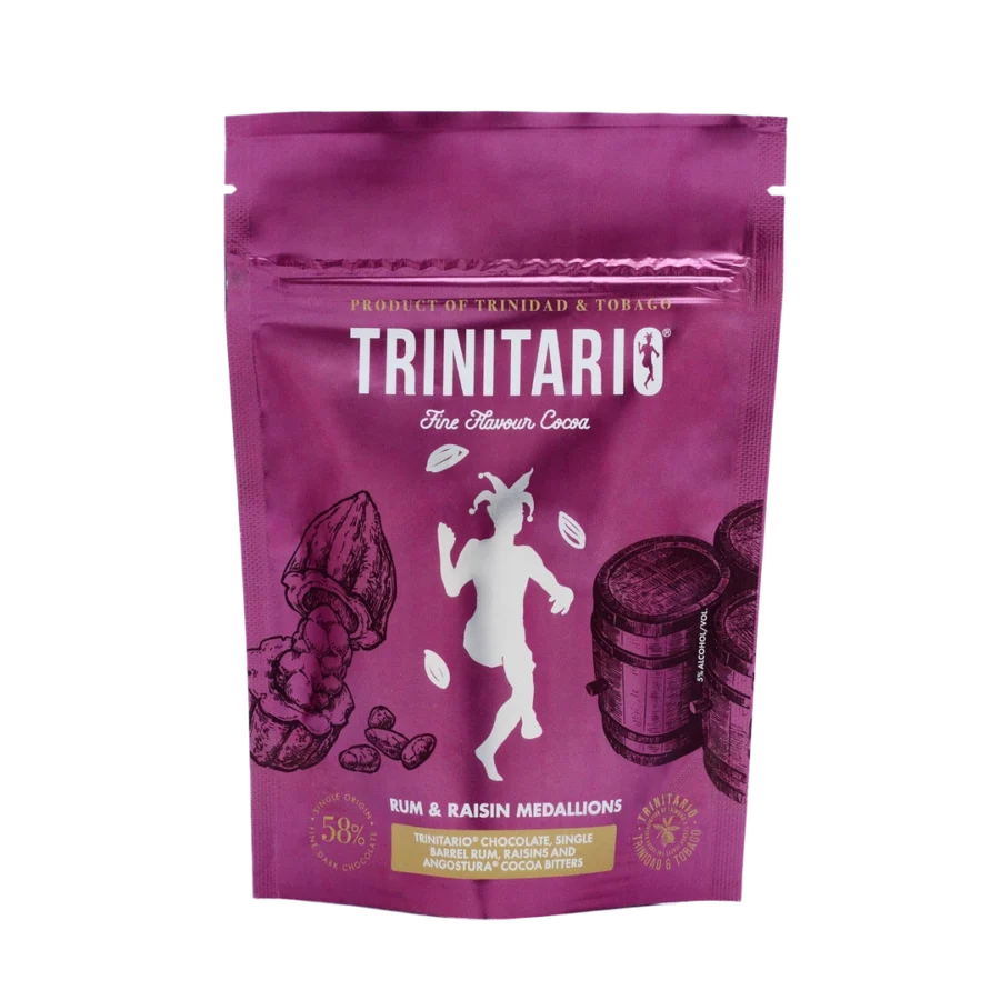 A purple pouch labelled "TRINITARIO Fine Flavour Cocoa," featuring cocoa pods, barrels, and a dancing figure. These Rum & Raisin Medallions are crafted with Caribbean cocoa for a truly fine flavour experience. | Trinitario