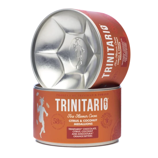 A round tin of single-origin chocolate Trinitario citrus and coconut medallions is shown, with the lid leaning against the container to display the logo and product details, highlighting its fine flavour cocoa origins. | Trinitario