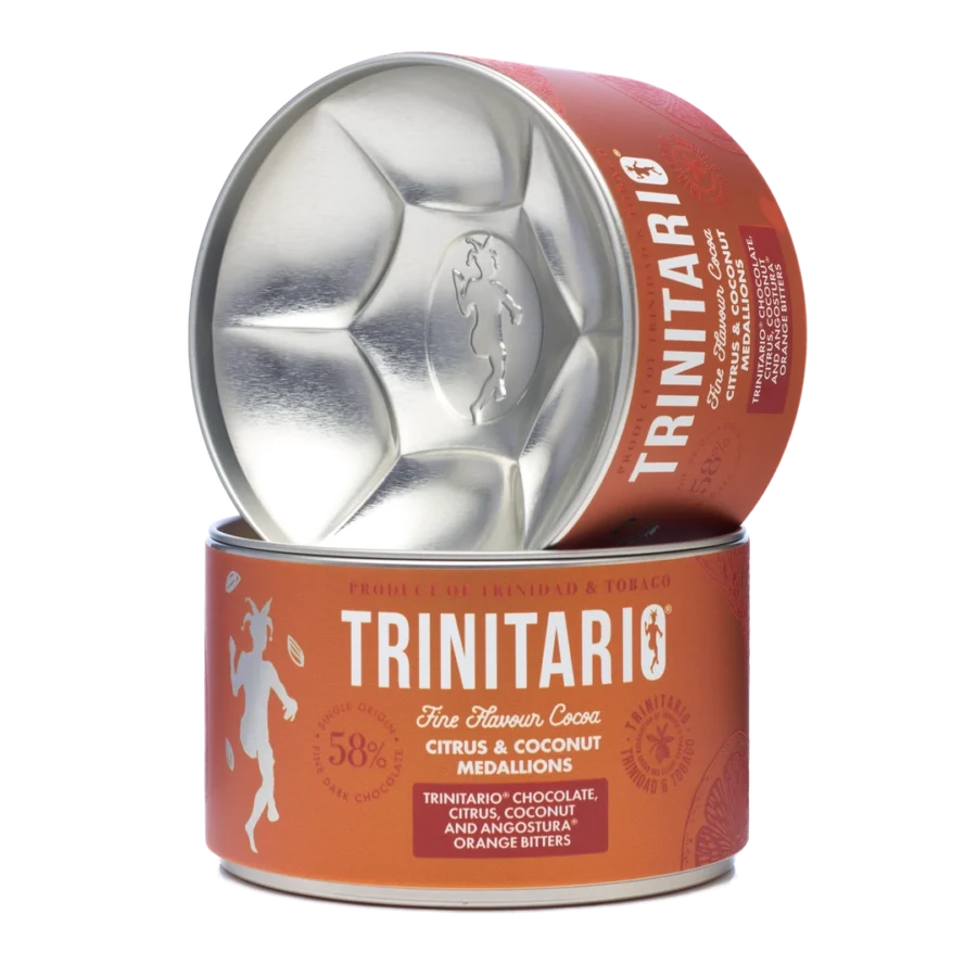 A round tin of single-origin chocolate Trinitario citrus and coconut medallions is shown, with the lid leaning against the container to display the logo and product details, highlighting its fine flavour cocoa origins. | Trinitario