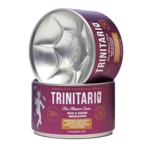 A round tin labelled "Trinitario Fine Flavour Cocoa" containing handcrafted rum and raisin chocolate medallions, with the lid leaning against the tin. | Trinitario