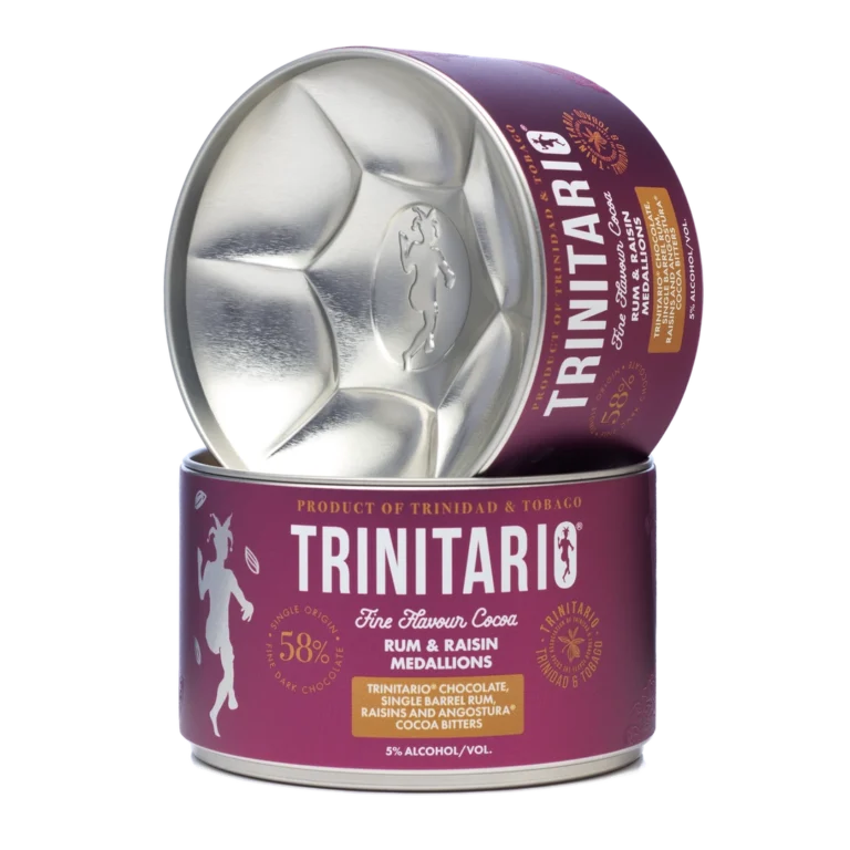 A round tin labelled "Trinitario Fine Flavour Cocoa" containing handcrafted rum and raisin chocolate medallions, with the lid leaning against the tin. | Trinitario