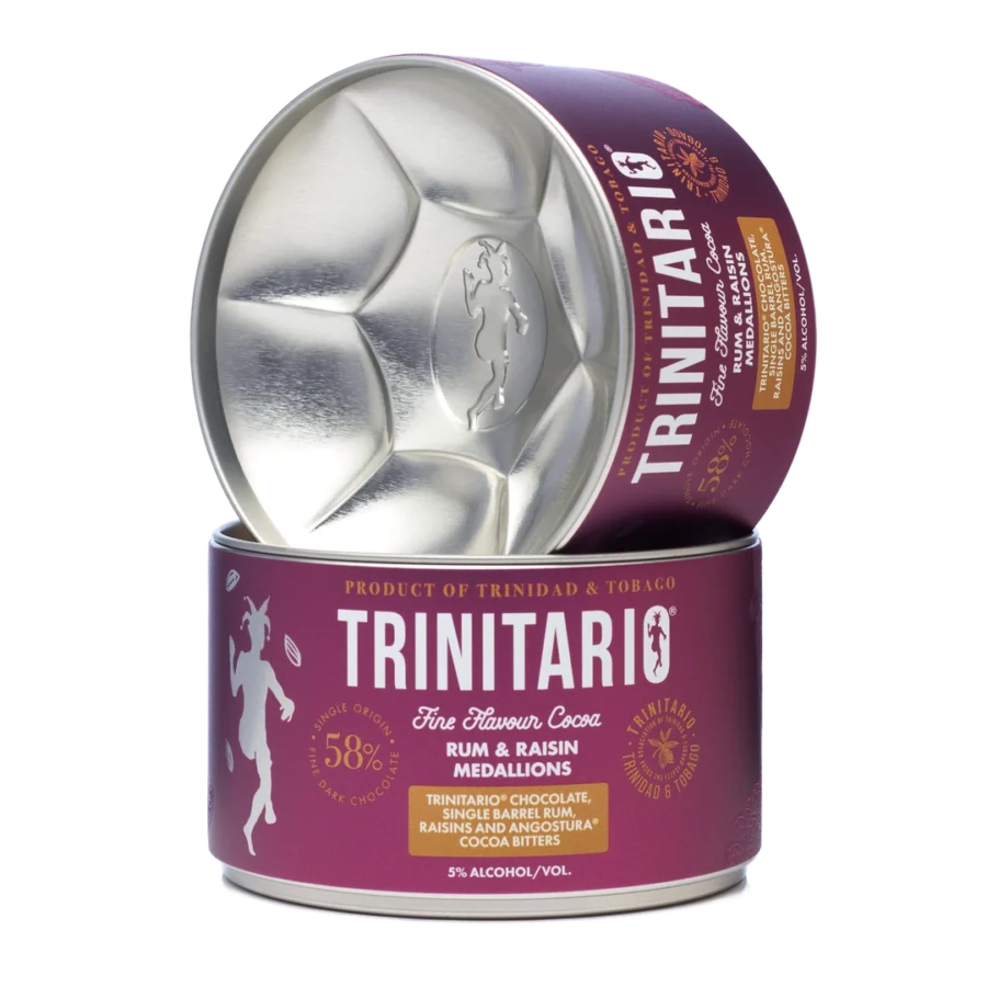 A round tin labelled "Trinitario Fine Flavour Cocoa" containing handcrafted rum and raisin chocolate medallions, with the lid leaning against the tin. | Trinitario