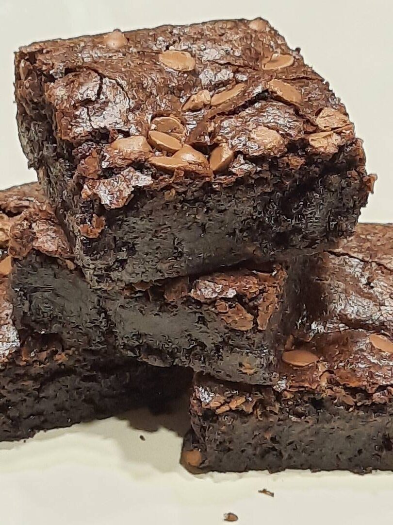 Stacked chocolate brownies topped with chopped nuts